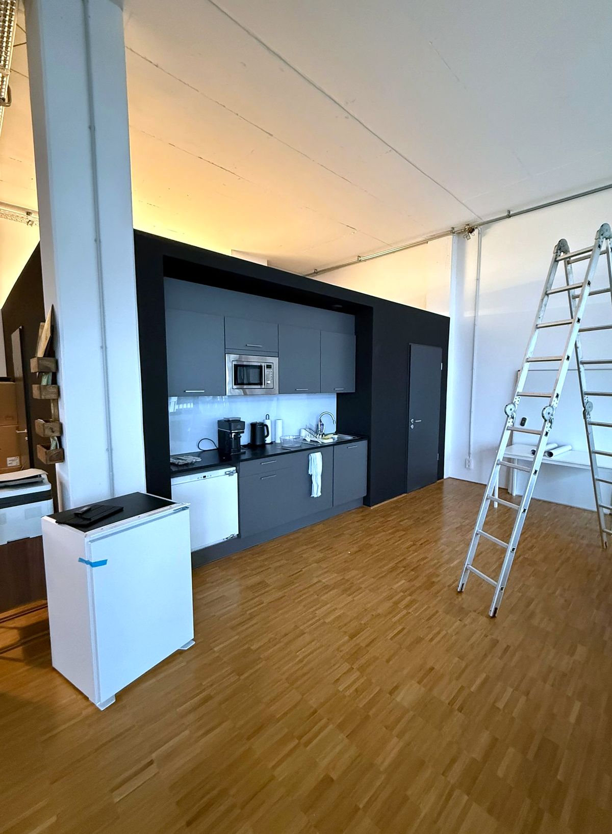 Loft-Büro vorher: offene Küchenzeile, Leiter im Raum, kein Sichtschutz
